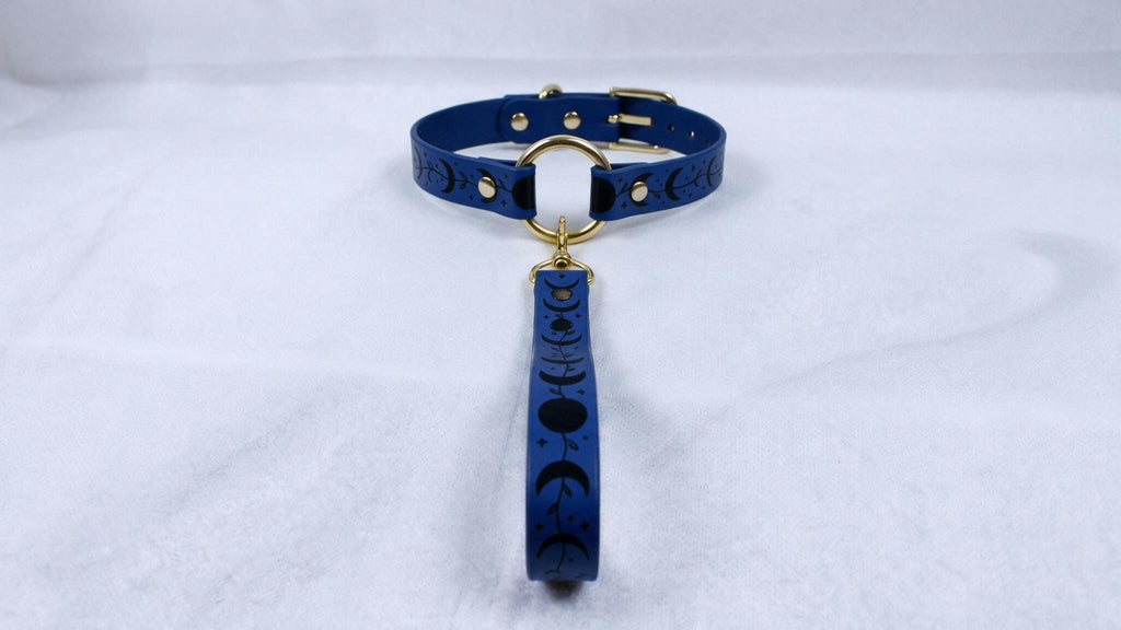 A blue collar with a moon and crescent design, featuring a gold buckle and a dangling handle.
