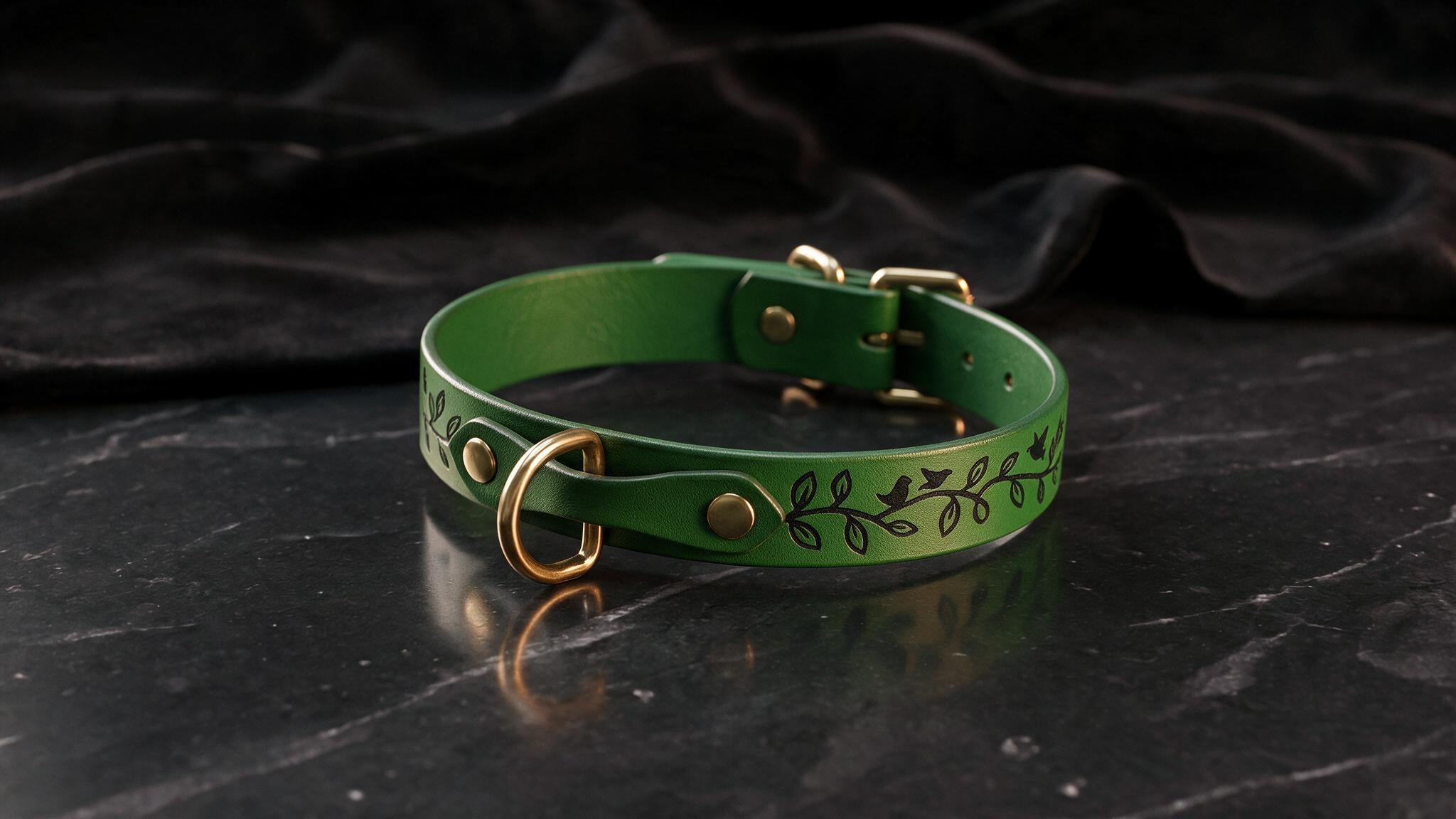 A green leather collar with a leaf design sits on a black marble surface.