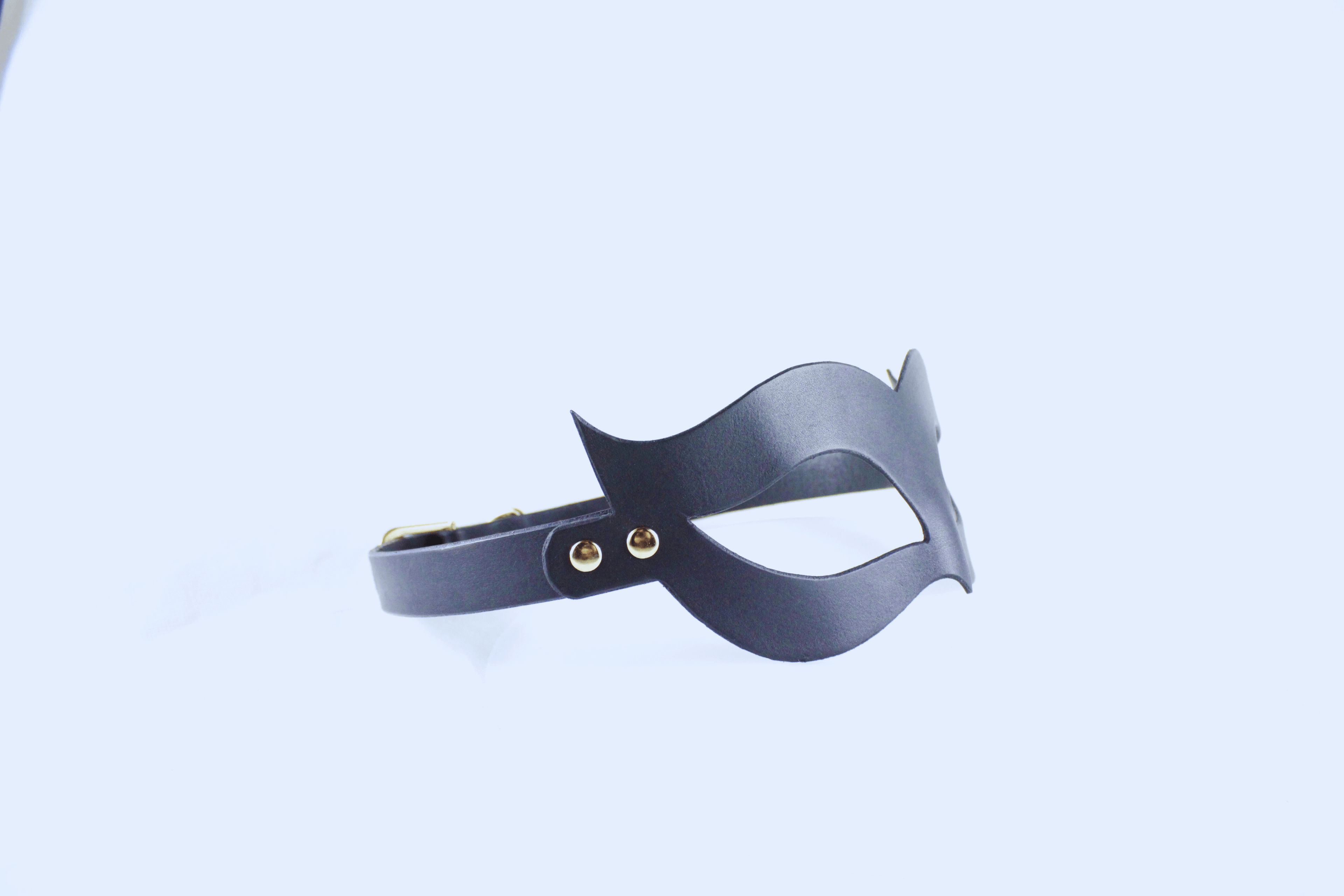 A black mask with a curved shape and two eye holes is shown against a plain white background.
