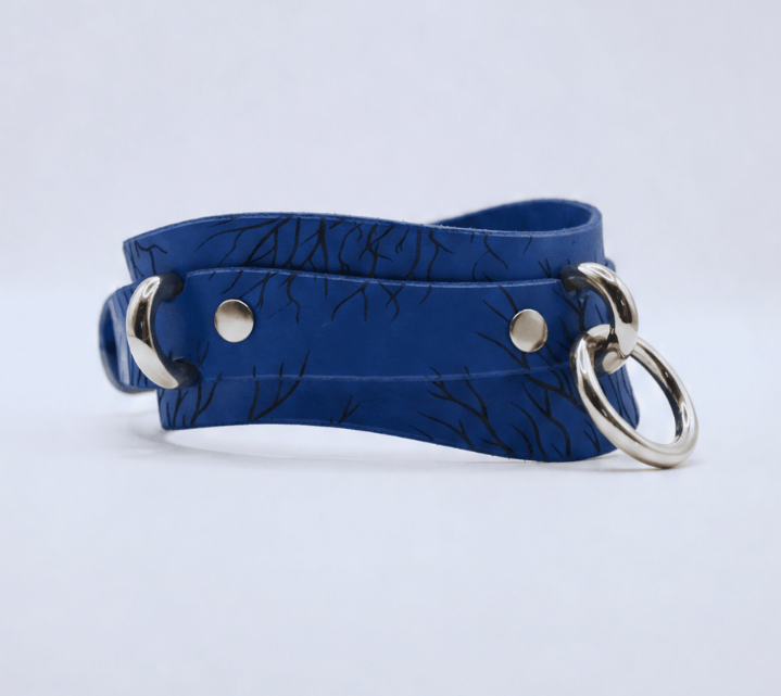 A blue leather choker necklace with a silver metal ring and two metal rings on either side.