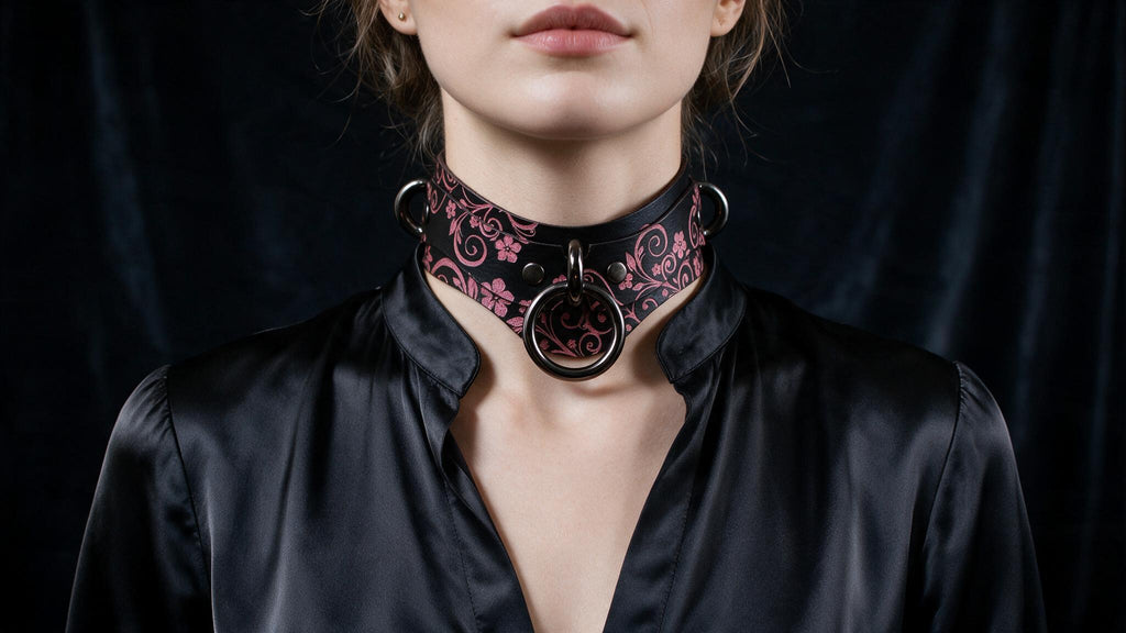 A woman wearing a black choker necklace with a floral pattern and a black ring on the front.