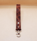 A brown leather strap with a metal clasp and hook attached to it.