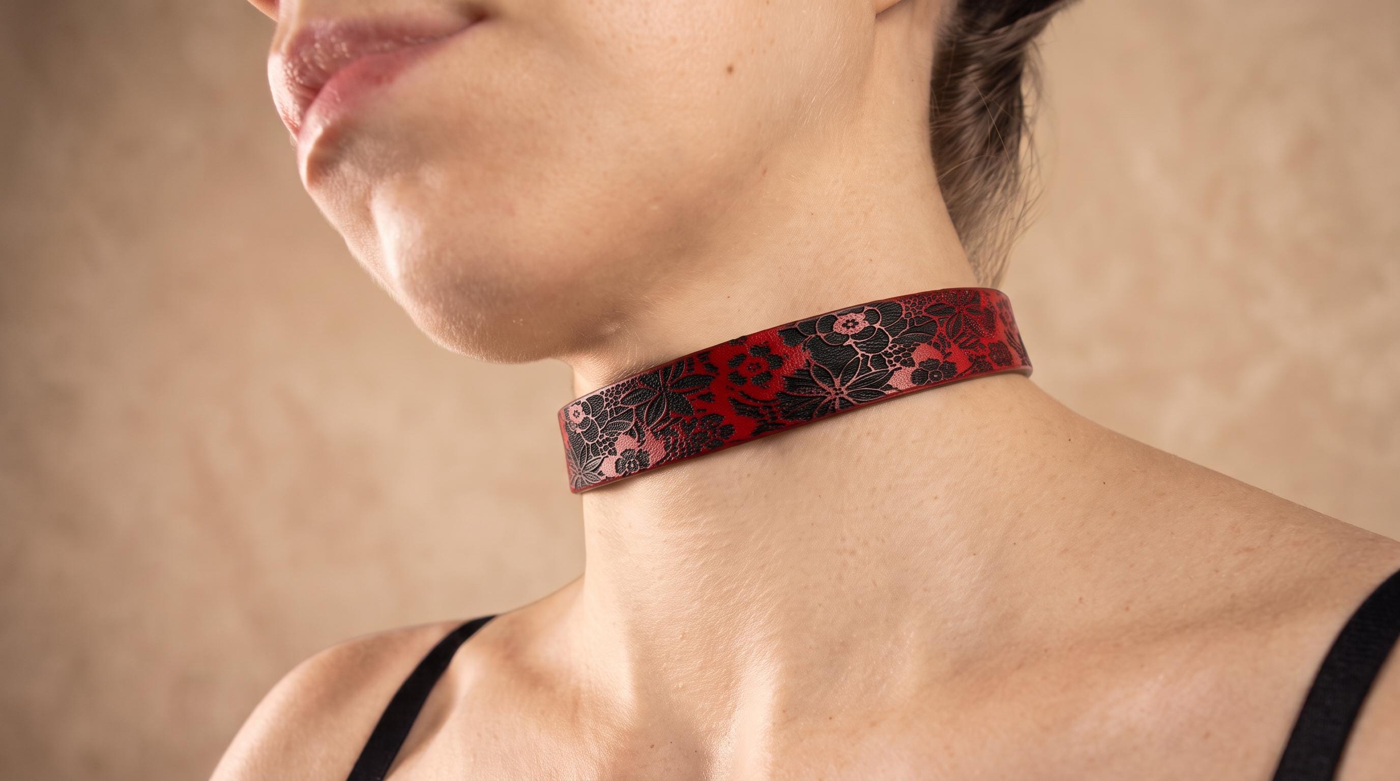 A close-up of a woman's neck and chest area wearing a red and black choker necklace.