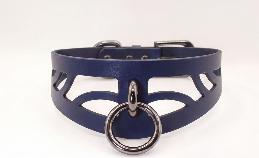 A close-up view of a dark blue choker necklace with a metal ring and a cutout design on the front.