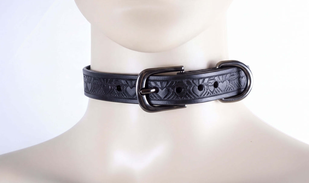 A close-up view of a black leather choker necklace with a decorative buckle.