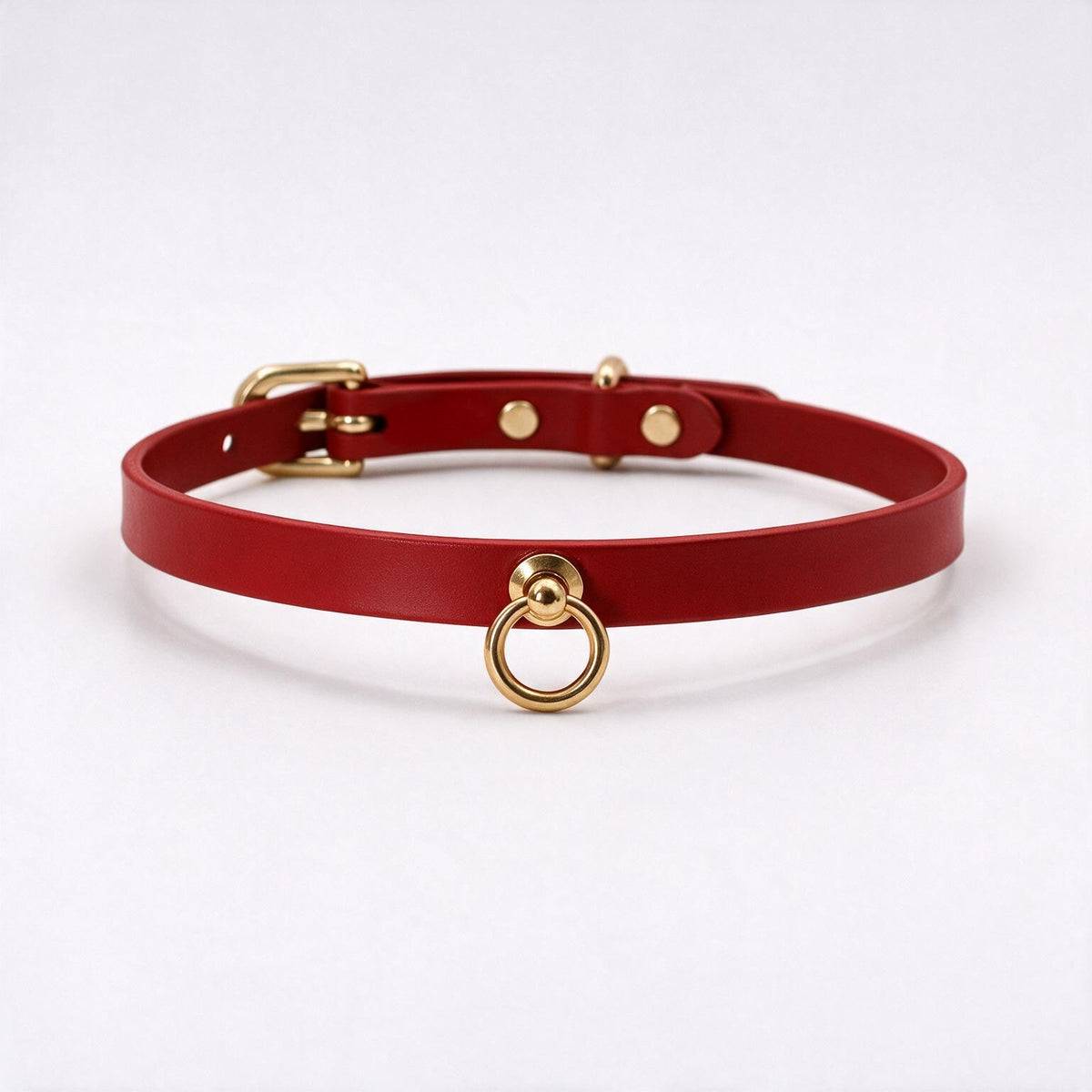 A red leather choker collar with a gold metal ring and buckle.