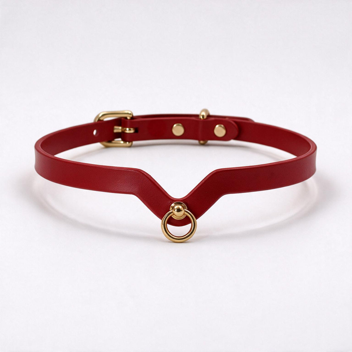 A red leather choker necklace with a gold-colored buckle and ring.