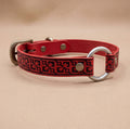 A red leather dog collar with a metal ring and buckle, featuring a decorative pattern on the strap.