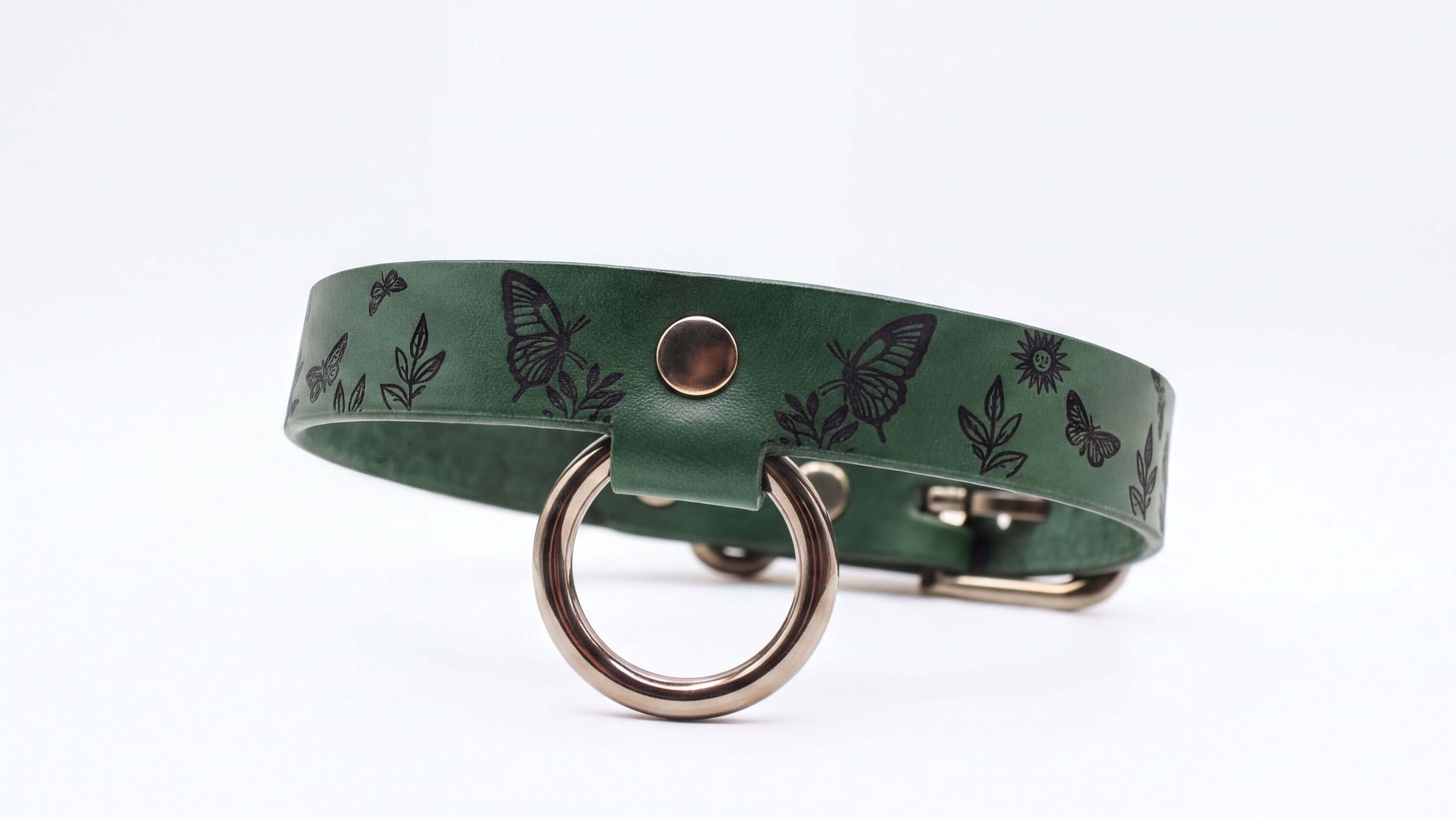 A green leather collar with a metal ring and butterfly designs printed on it.
