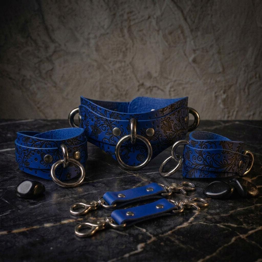 A set of blue leather straps with metal rings and buckles, arranged on a dark surface.