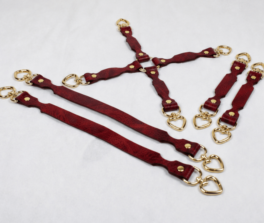 a collection of red leather straps with gold-colored heart-shaped buckles, arranged in various orientations on a white background.
