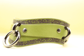 A green leather strap with metal rings and decorative patterns on it.