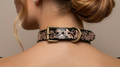 A close-up view of a woman's neck and shoulders, focusing on a decorative leather choker necklace with floral patterns and a metal buckle.