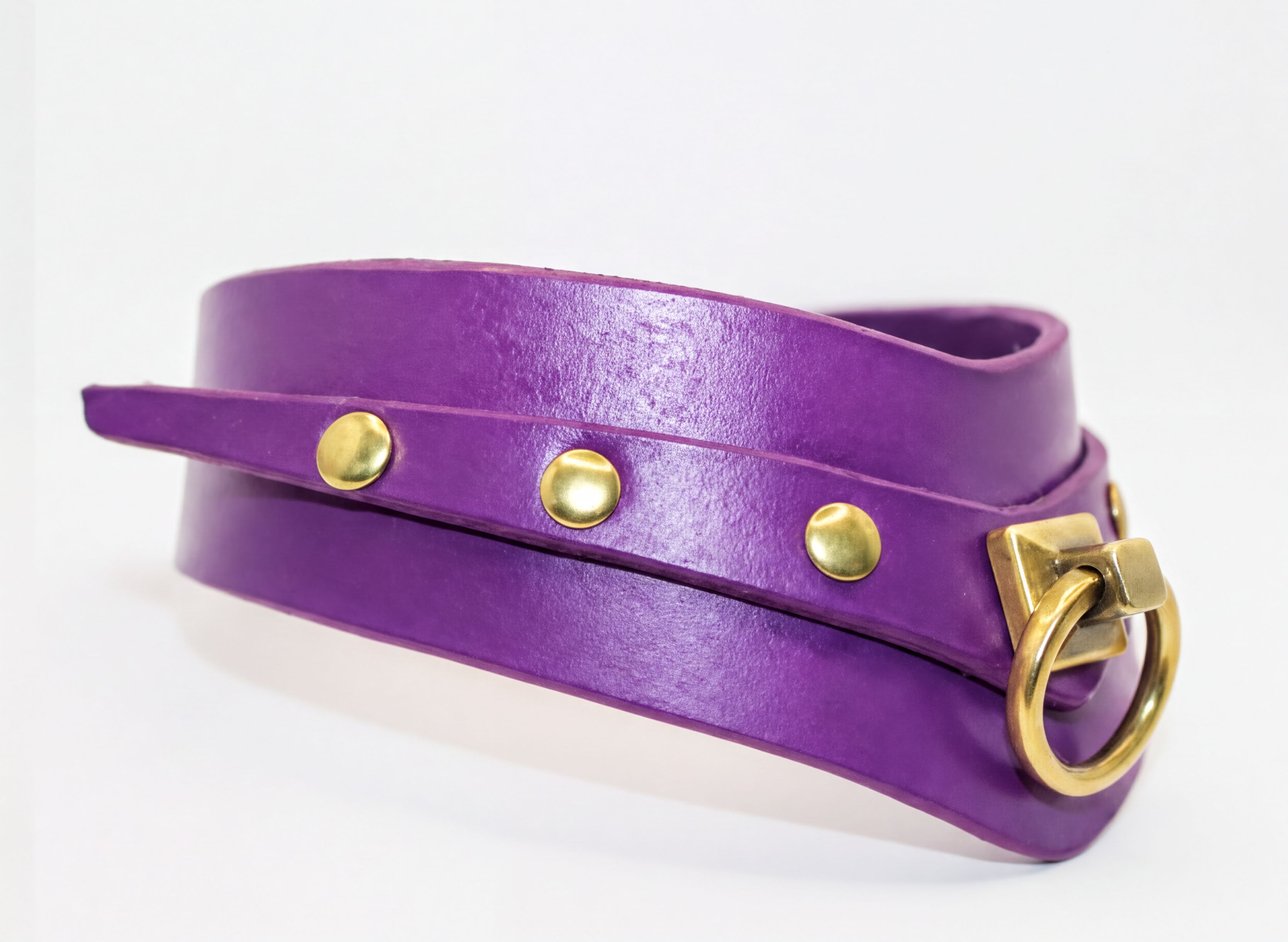 A purple leather choker collar with gold hardware, including a ring and three metal studs, is shown in the image.