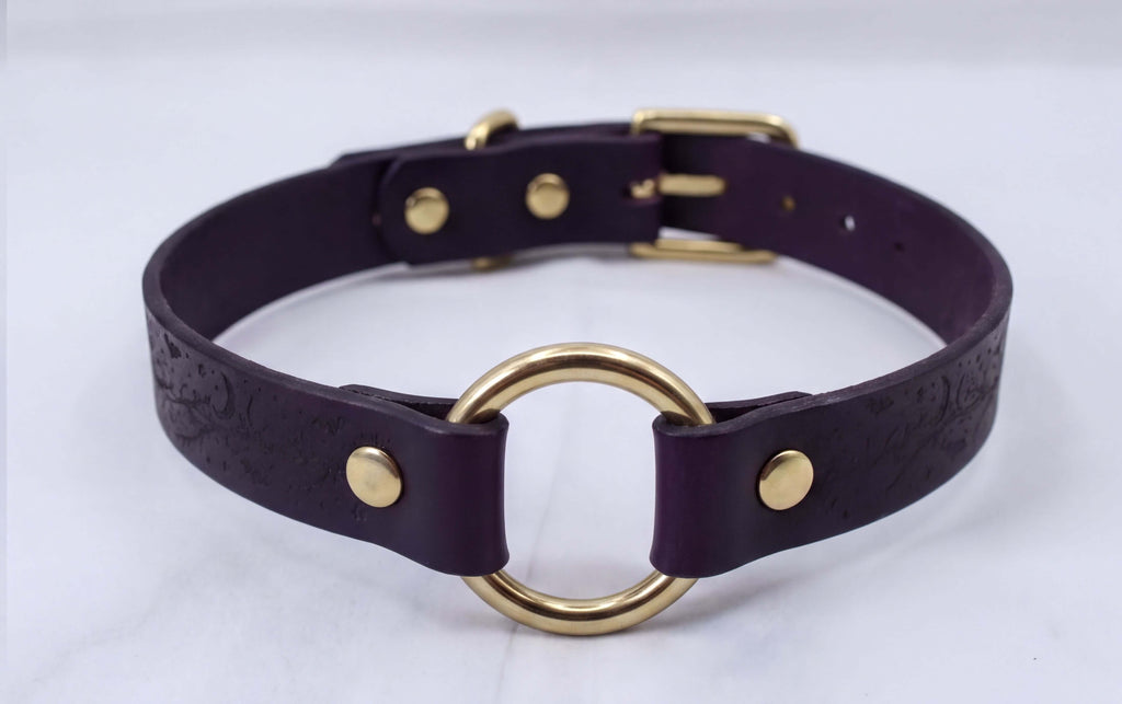 A purple leather choker collar with a gold ring and buckle.