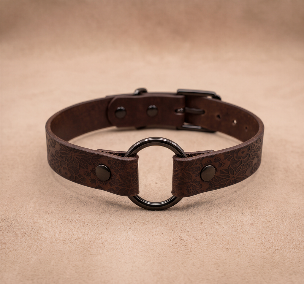 A brown leather choker collar with a black metal ring and buckle.