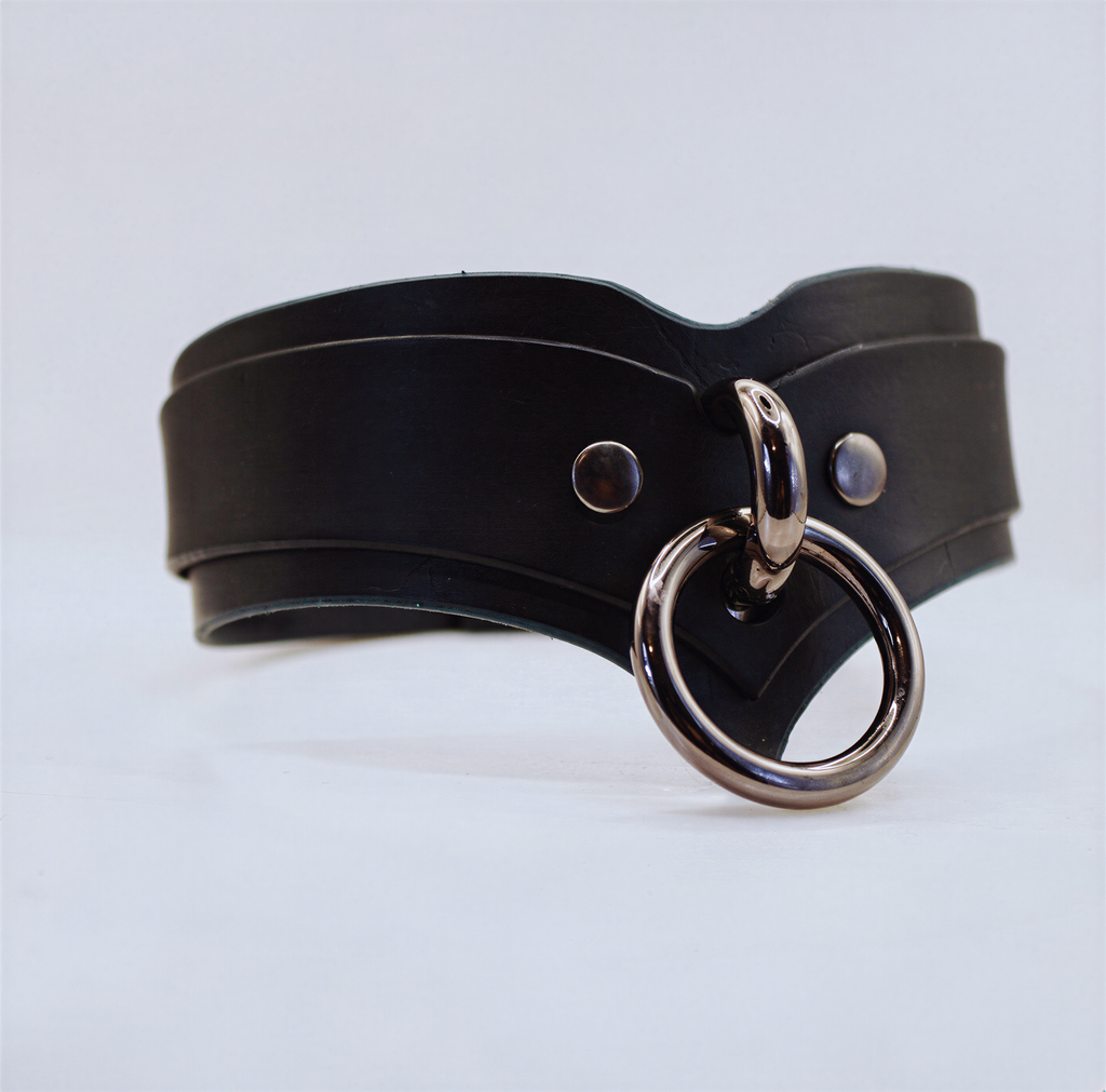 A black leather choker necklace with a metal ring and two metal studs on the front.