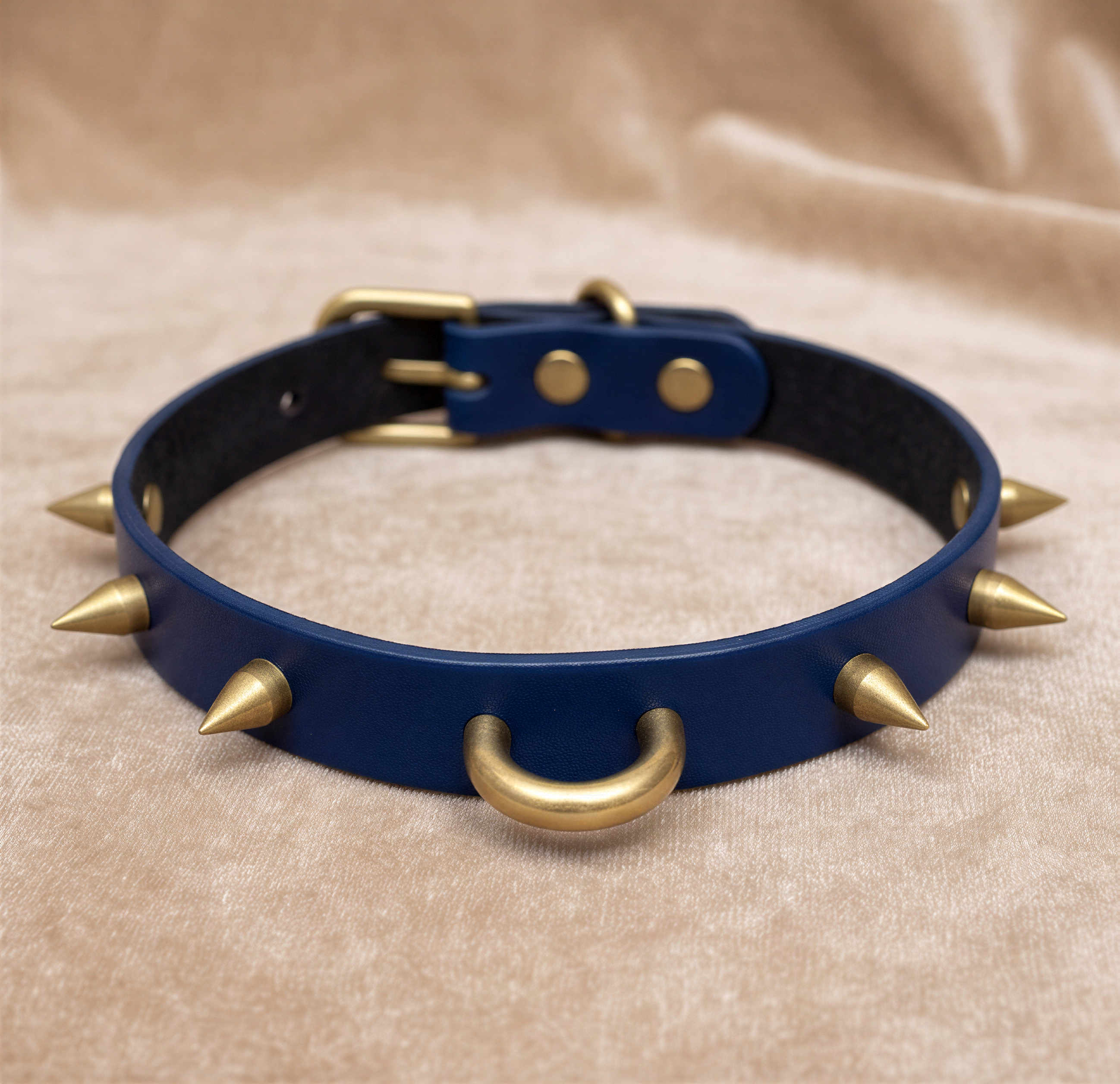 A blue leather dog collar with gold spikes on it.