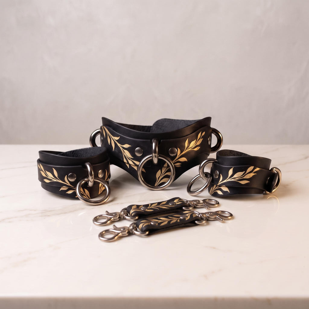 A set of black leather straps with gold leaf designs, arranged on a white marble surface.
