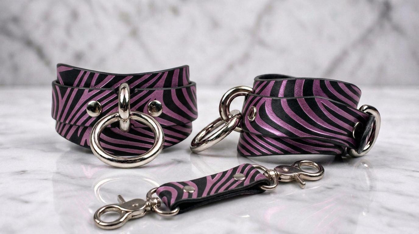 a pair of zebra-striped leather straps with metal rings and buckles, arranged on a marble surface.