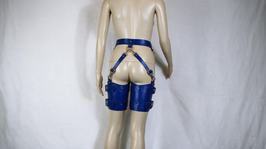 A mannequin wearing blue leather straps and garter belts against a white background.