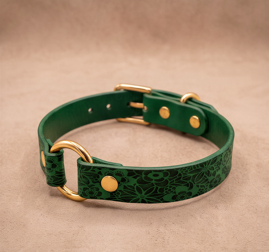 A green leather dog collar with a floral pattern and gold hardware.