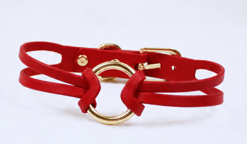 A red leather choker necklace with a gold-colored metal buckle.
