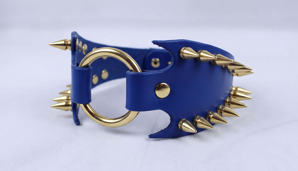 A blue leather choker necklace with gold spikes protruding from it.