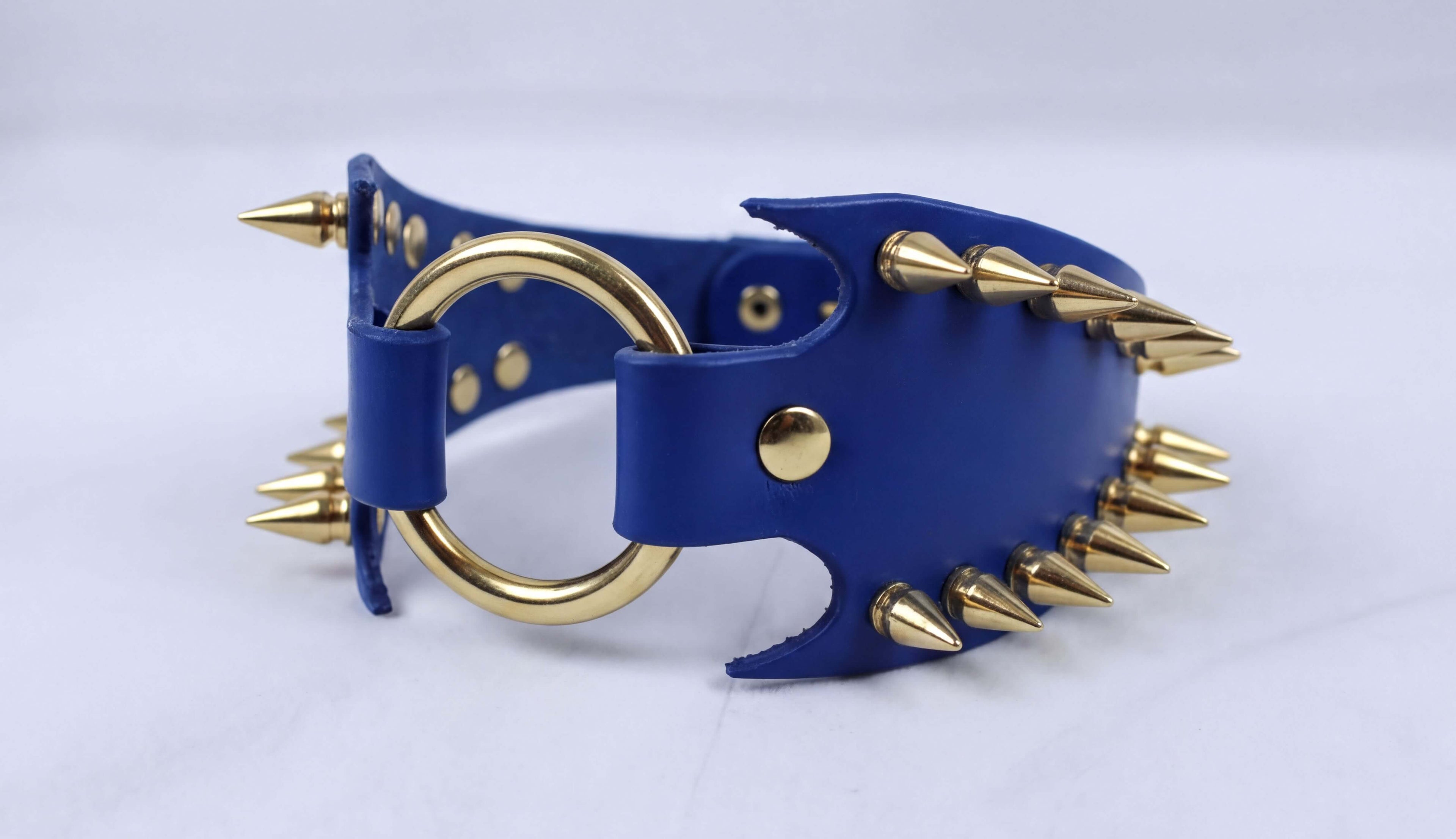 A blue leather choker necklace with gold spikes protruding from it.
