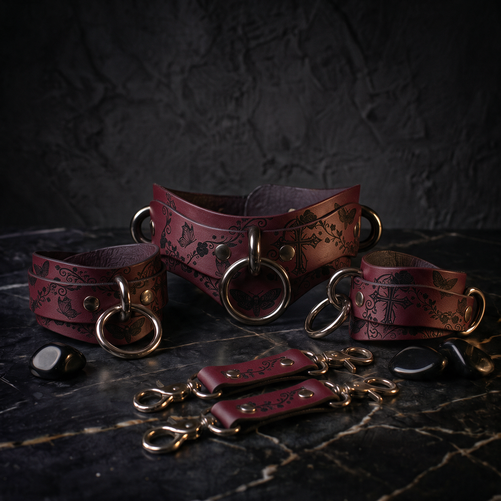 A set of burgundy leather choker necklaces and straps with intricate floral designs, displayed on a dark surface.