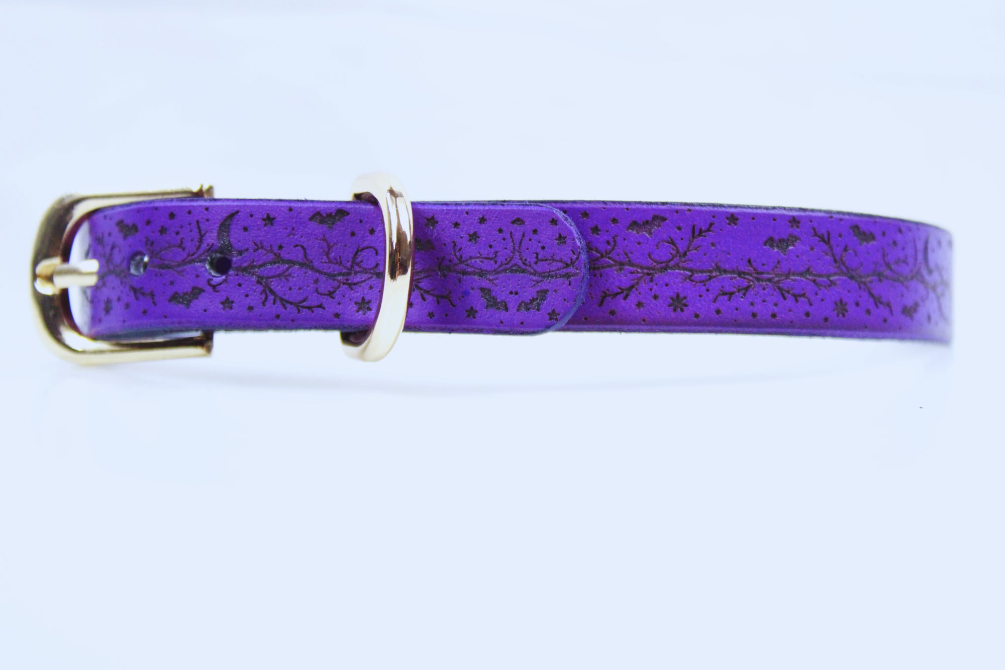 A purple leather belt with a gold buckle, featuring a pattern of stars and bats on the surface.