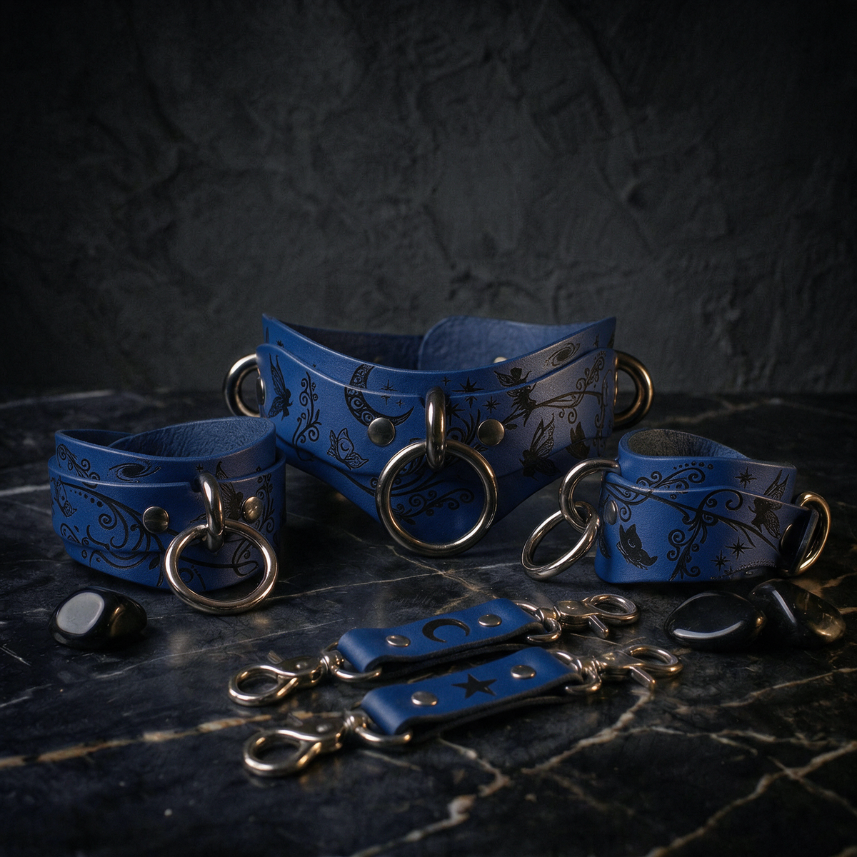 A collection of blue leather straps with metal rings and buckles, arranged on a dark surface.