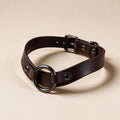 A brown leather choker collar with a metal ring and buckle.