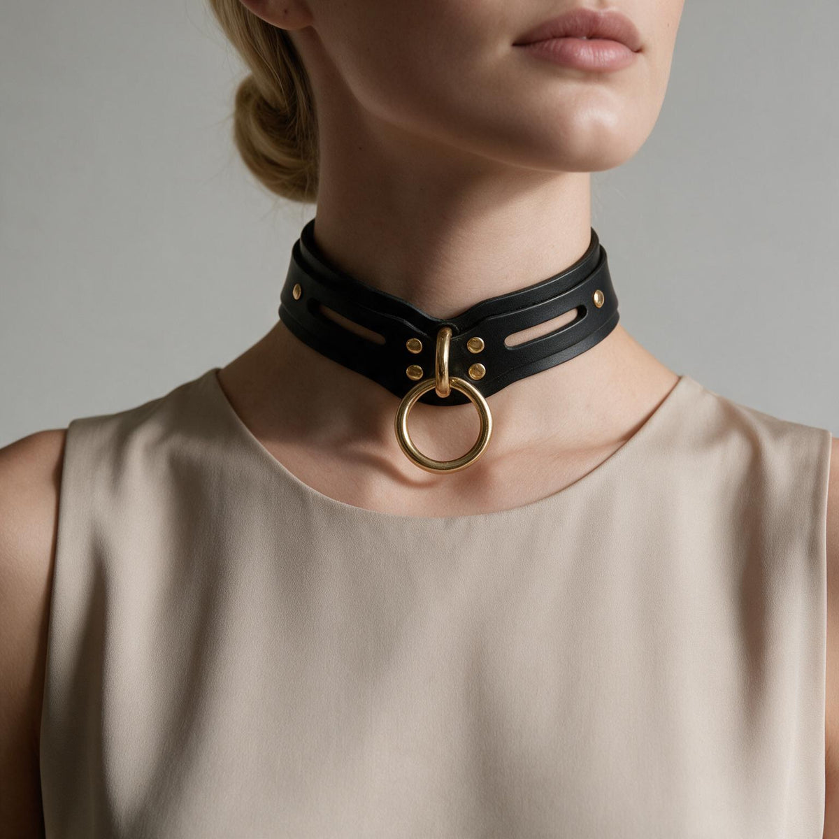 A woman wearing a black choker necklace with a gold ring on it.
