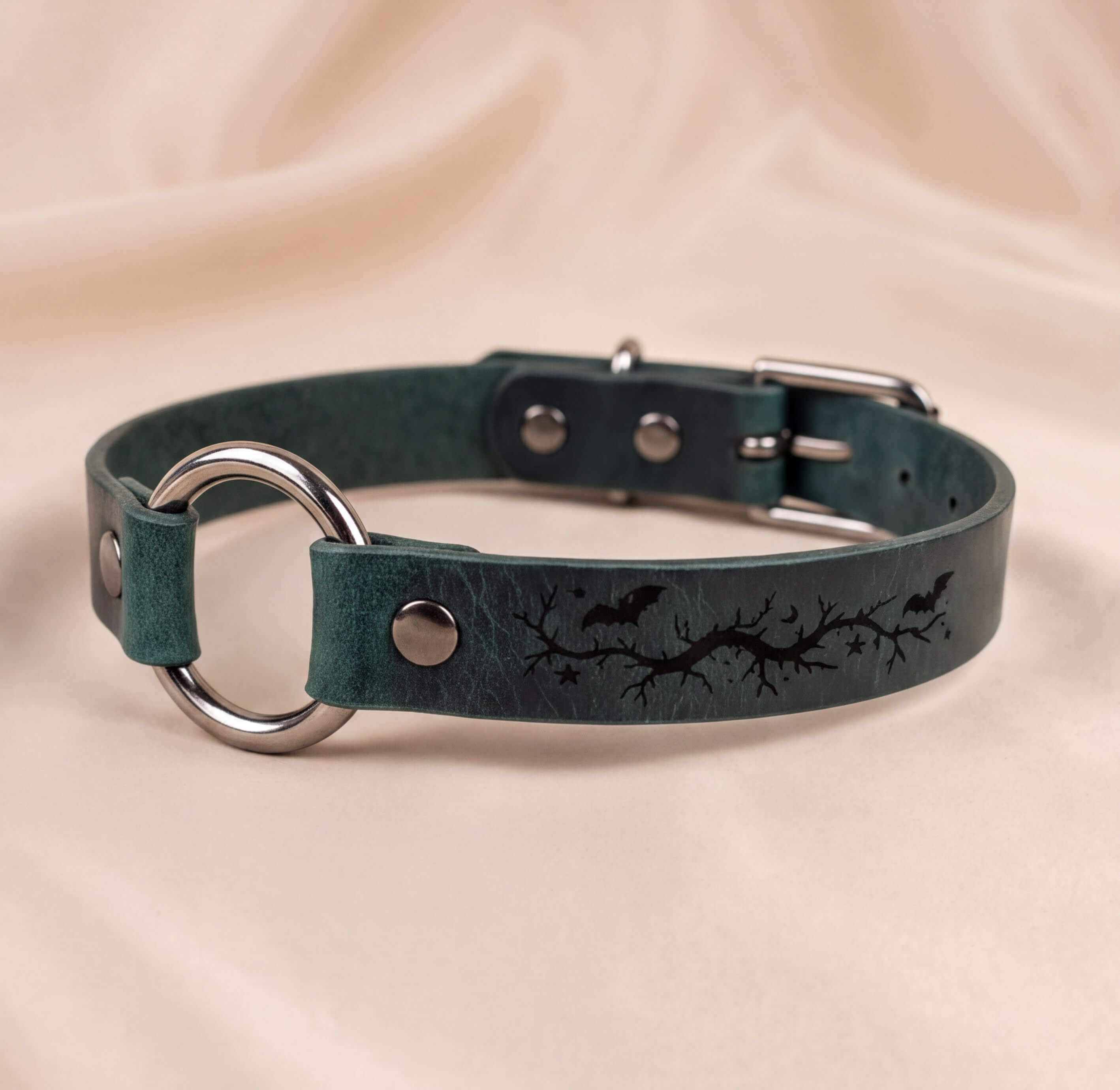 A dark green leather collar with a metal ring and a graphic design on the strap.