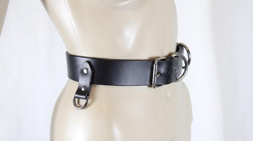 A mannequin wearing a black leather belt with metal buckles.