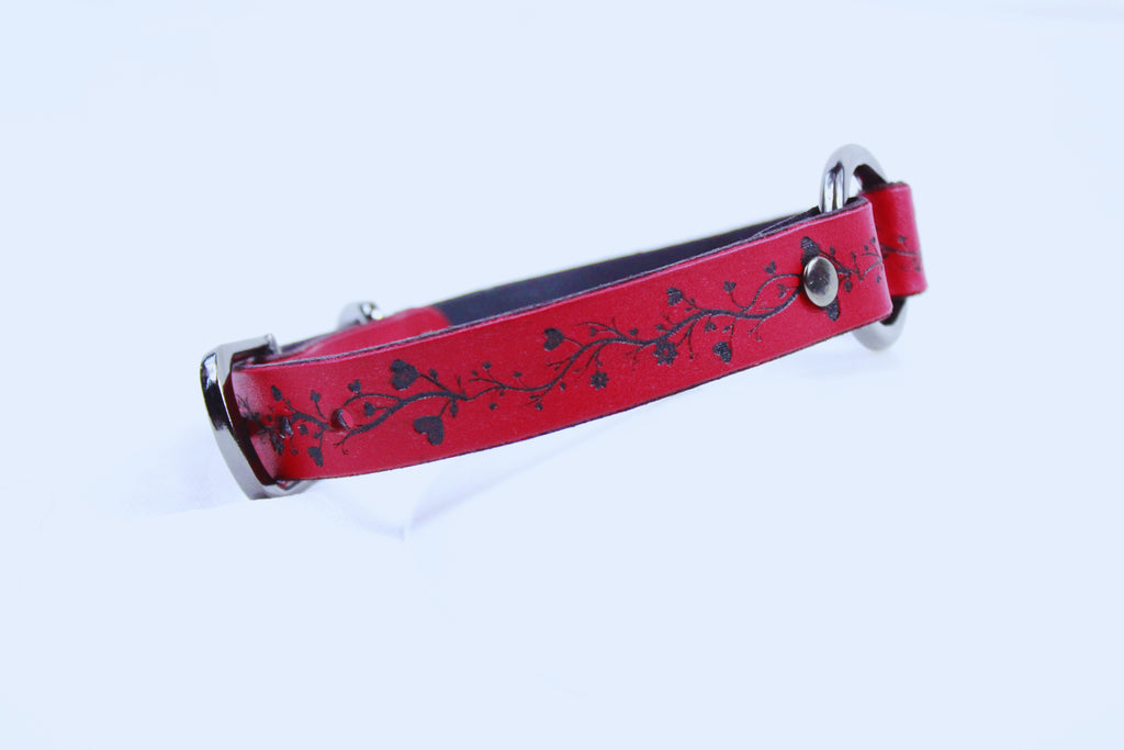 A red leather dog collar with a black floral design on it.