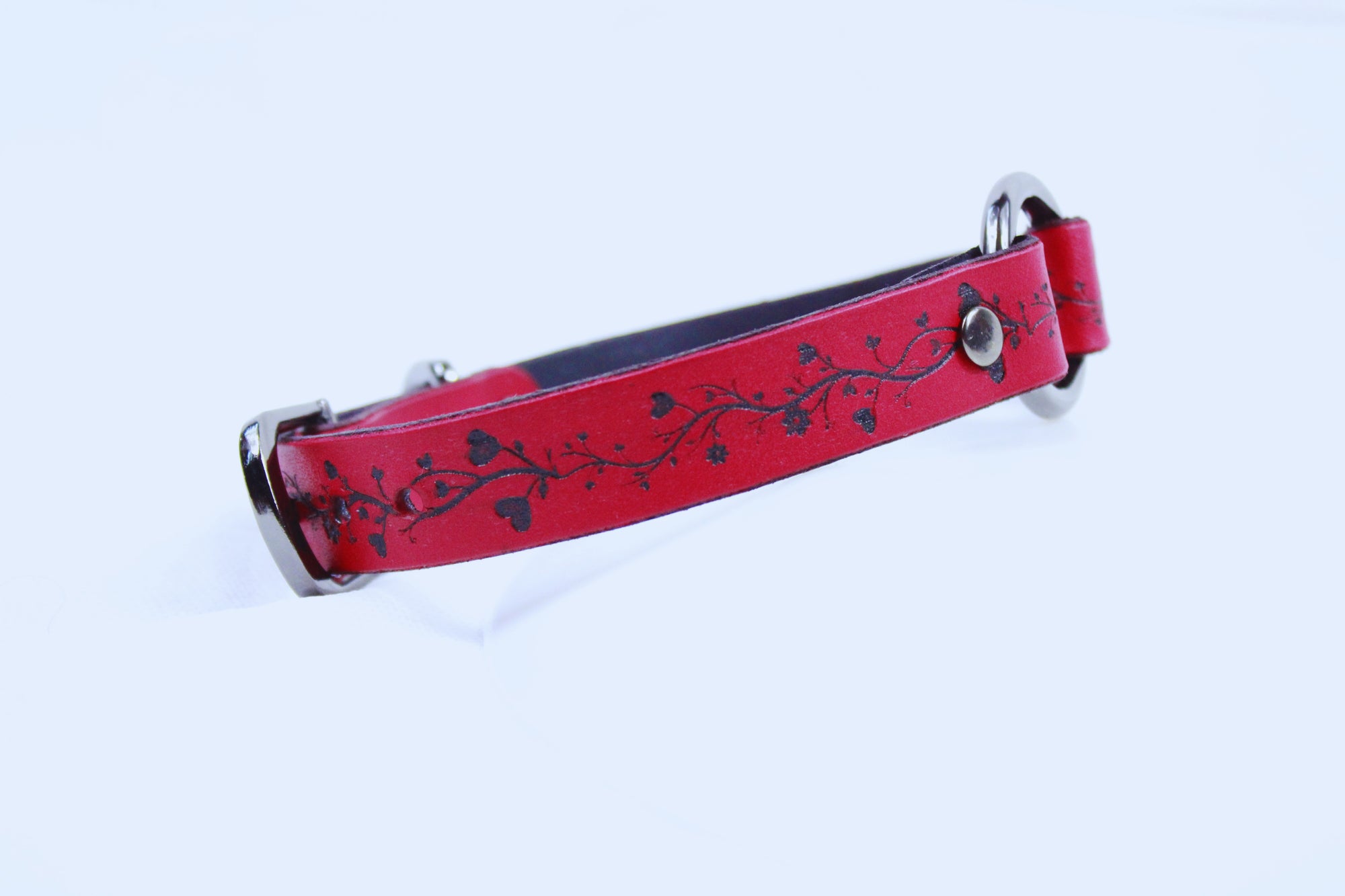 A red leather dog collar with a black floral design on it.