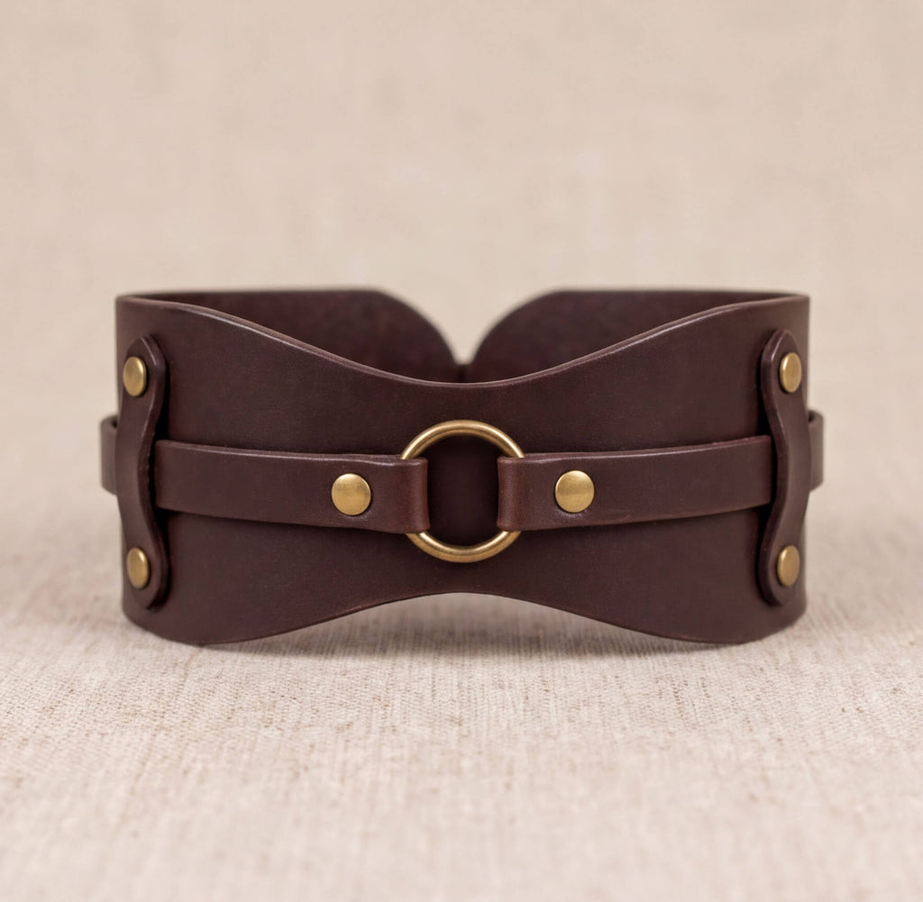 A brown leather corset with a metal ring and buckle fastening.