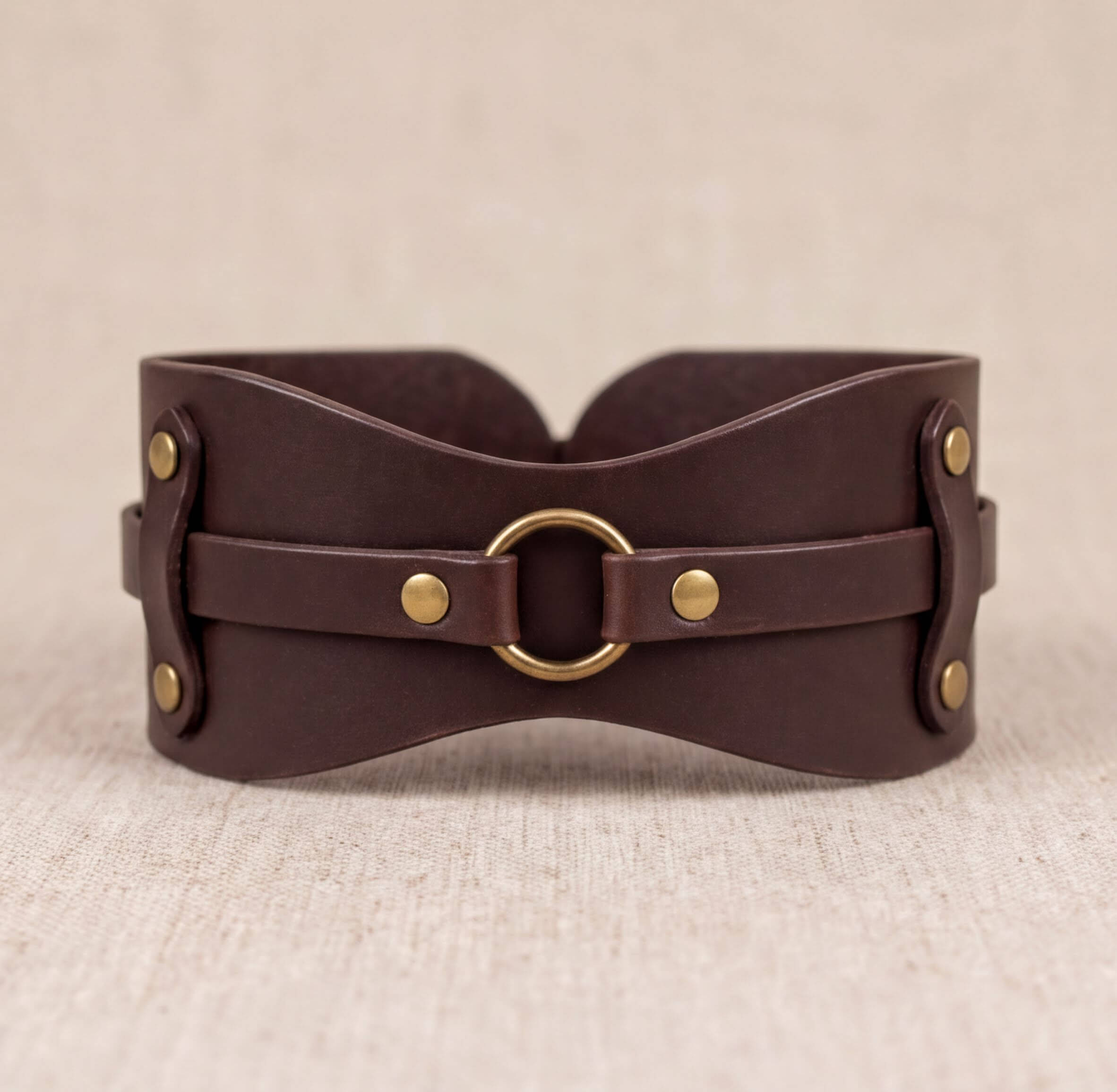 A brown leather corset with a metal ring and buckle fastening.