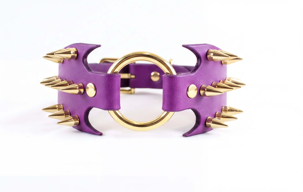 A purple leather choker necklace with gold spikes protruding from it.