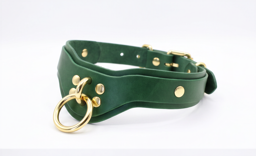 A green leather choker collar with gold hardware, including a ring and several small holes, is shown in the image.