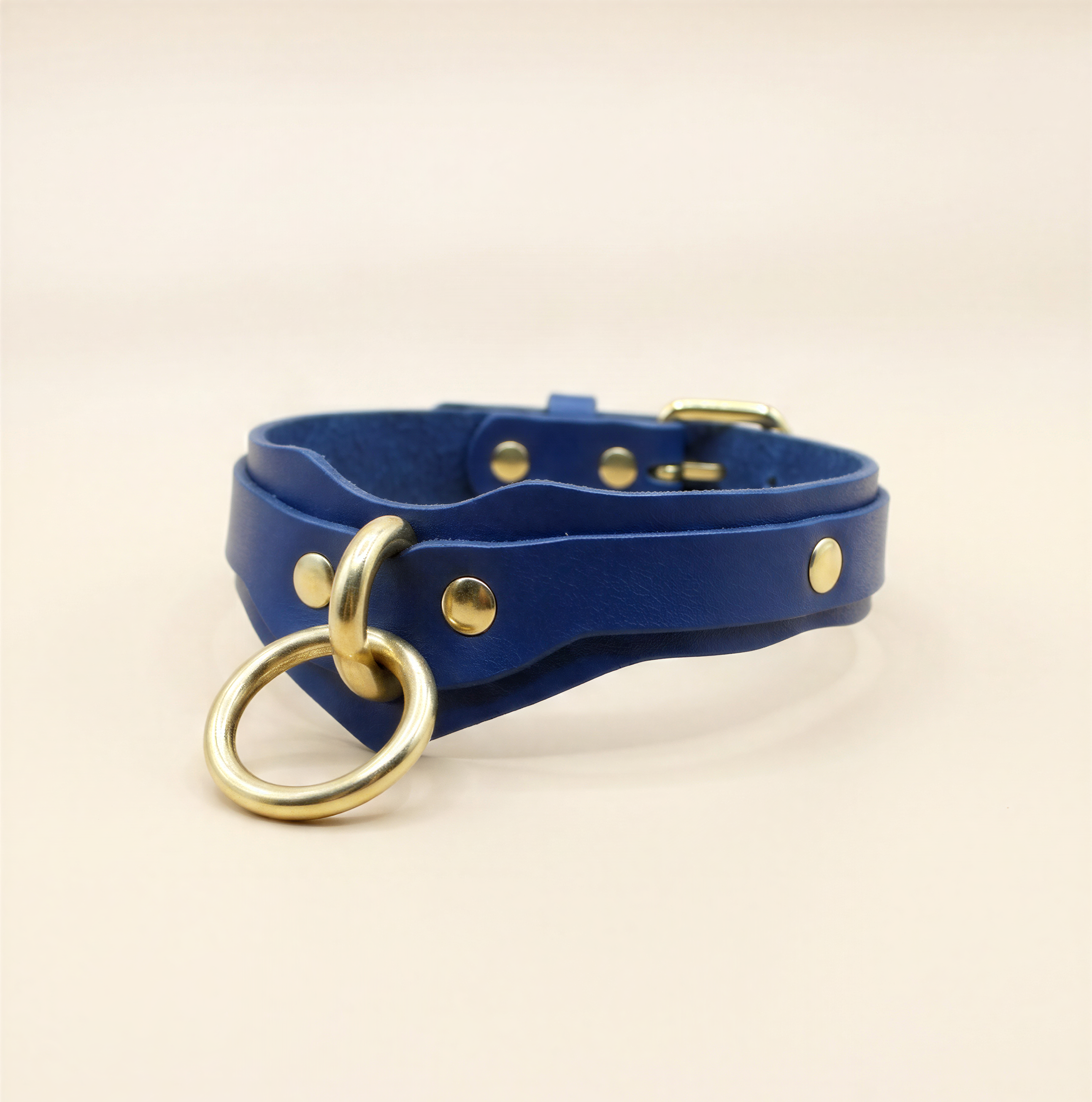 A blue leather choker necklace with a gold-colored metal ring and buckle.