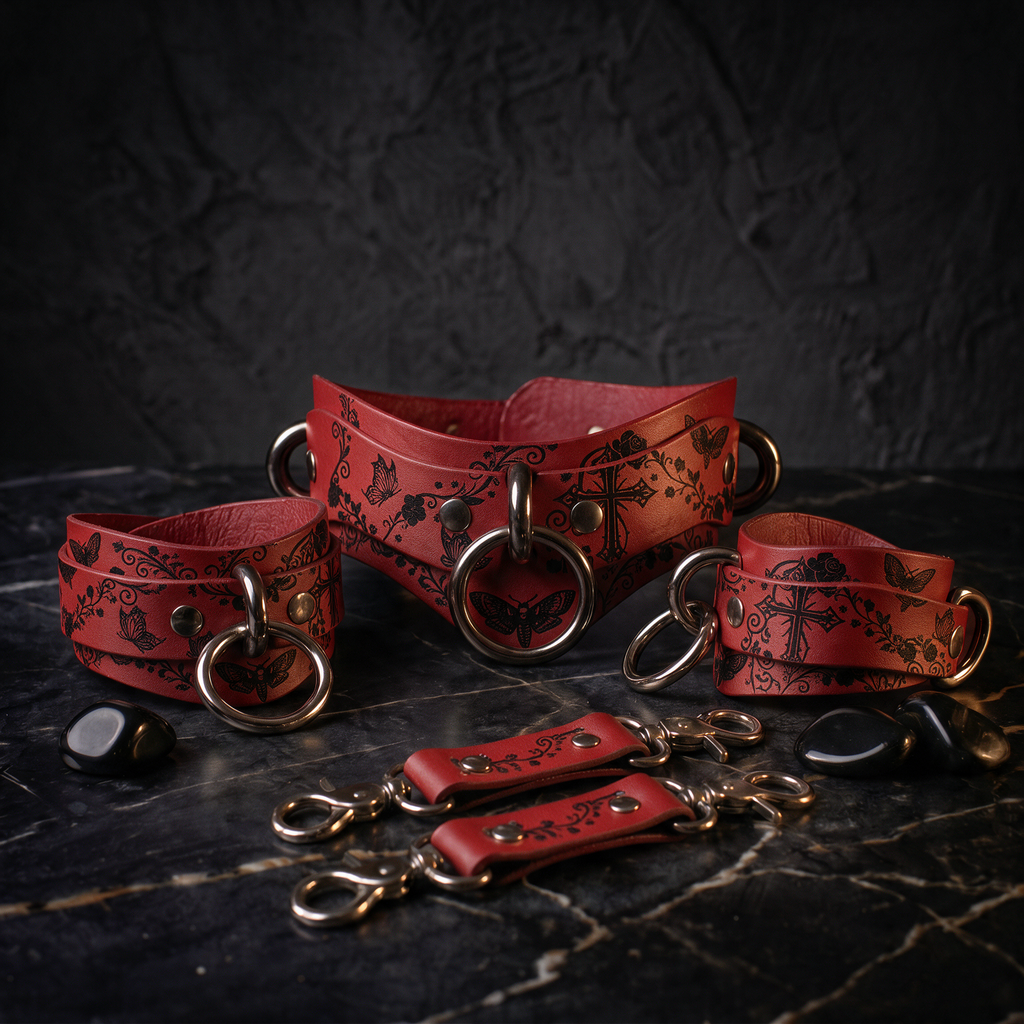 A set of red leather choker necklaces with metal rings and decorative patterns, displayed on a dark surface.