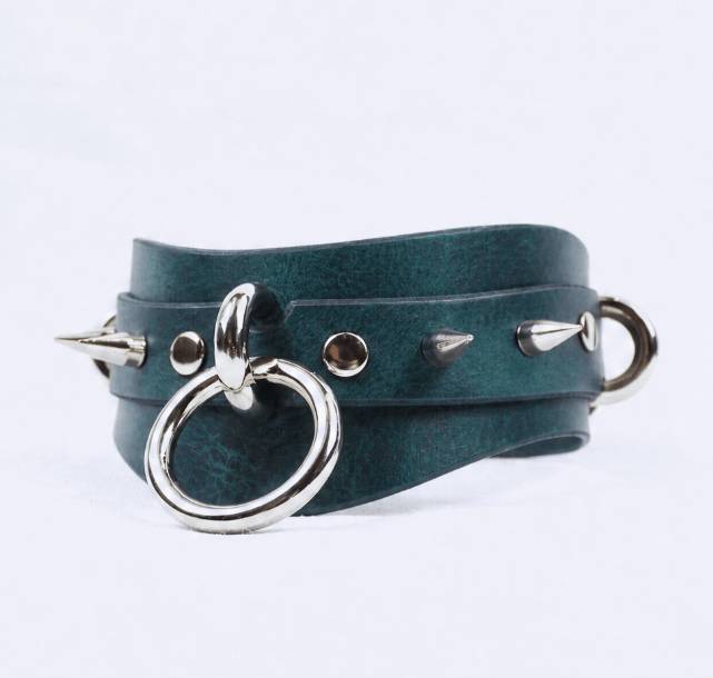 A dark green leather choker necklace with silver metal spikes protruding from it.
