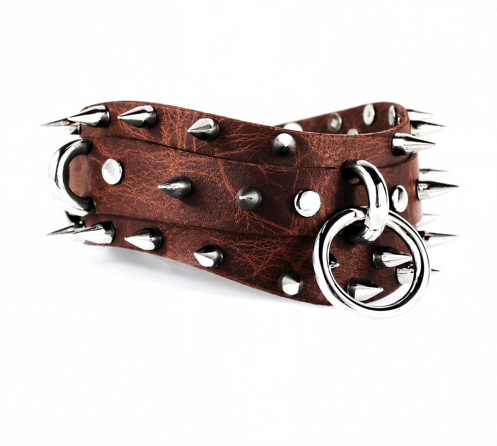 A brown leather belt with silver spikes and a metal ring on it.