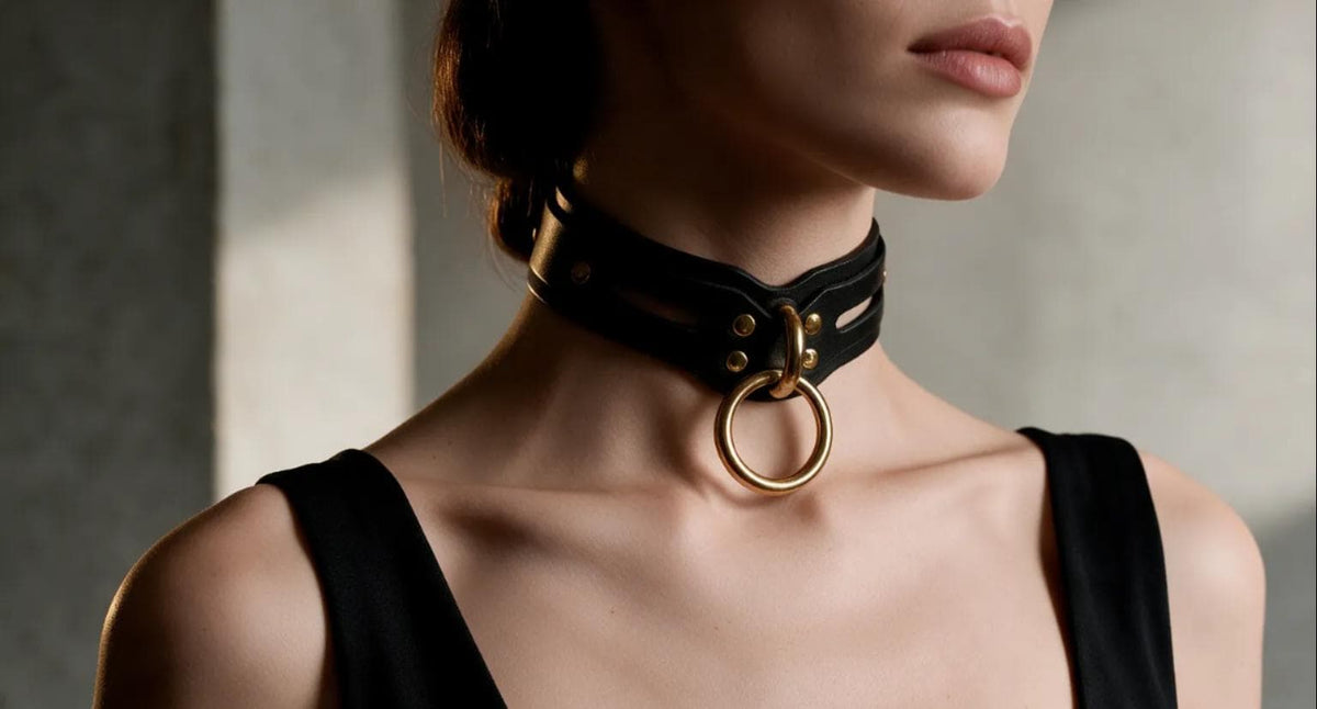 A woman wearing a black dress with a large, ornate gold ring on her neck.