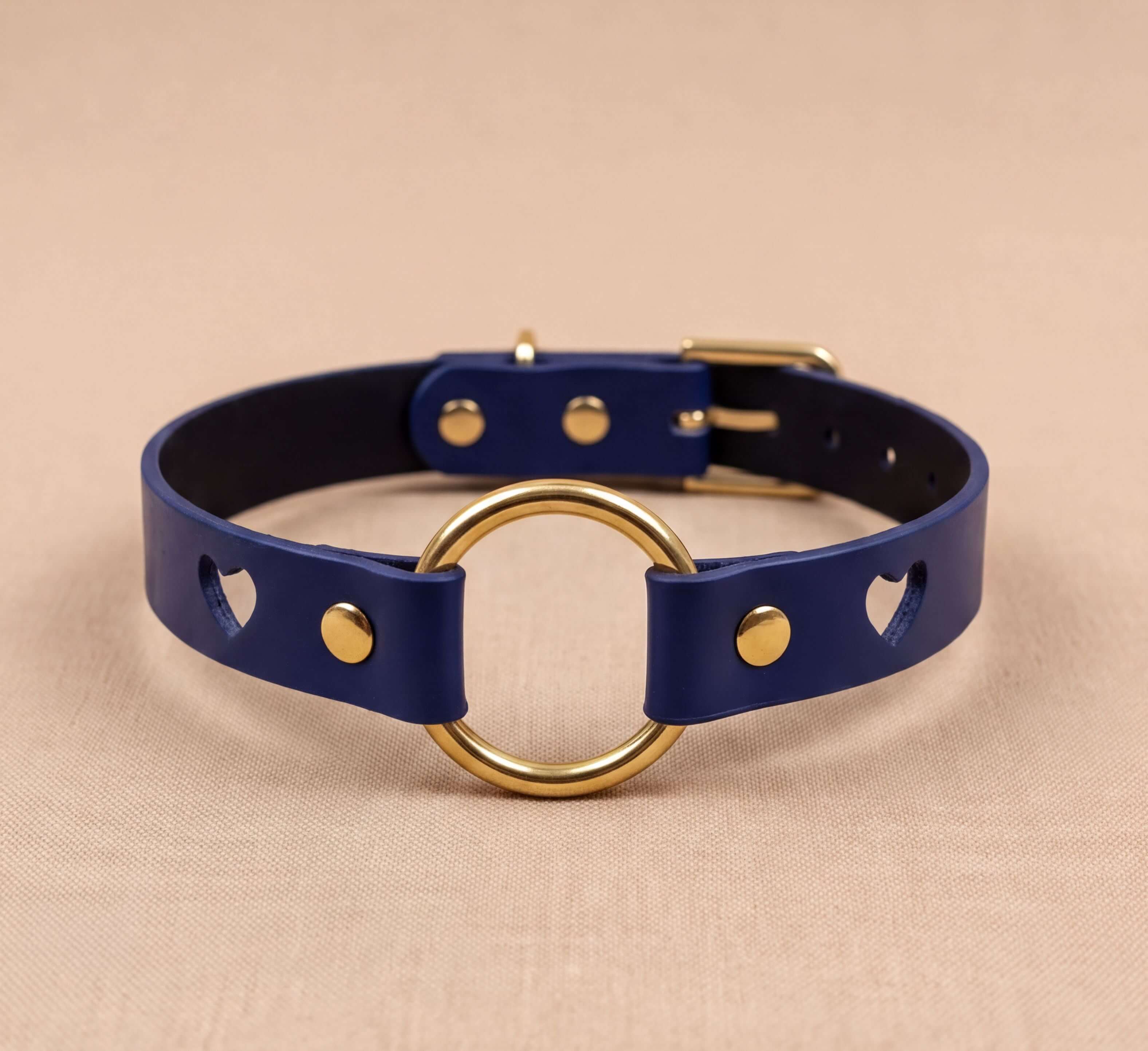 A blue leather choker necklace with a gold-colored ring and a black leather buckle.