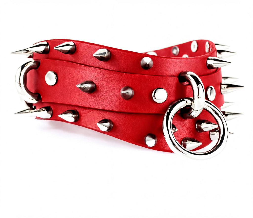 A red leather belt with silver spikes and a metal ring on it.