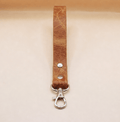 A brown leather strap with a metal clasp and hook attached to it.